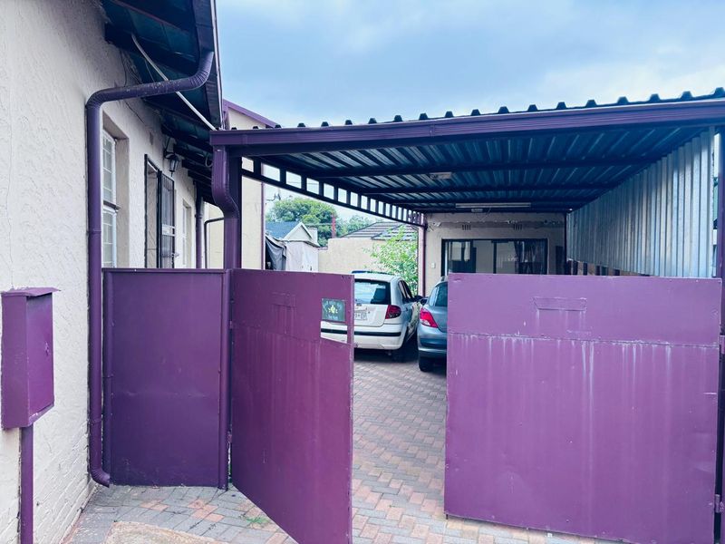 A covered carport area with a paved driveway and secure metal gate access.
