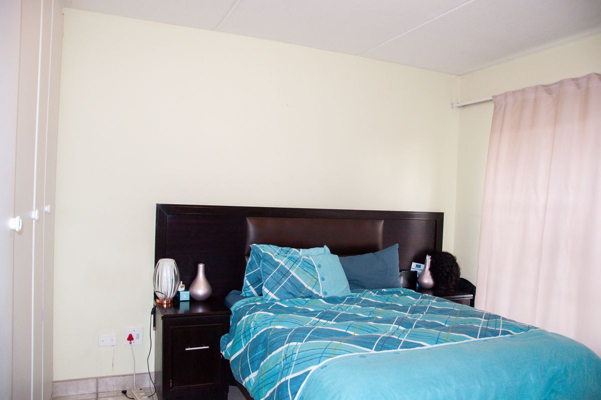 A bedroom featuring built-in cupboards and a dark wood headboard, providing a functional and neutral space.