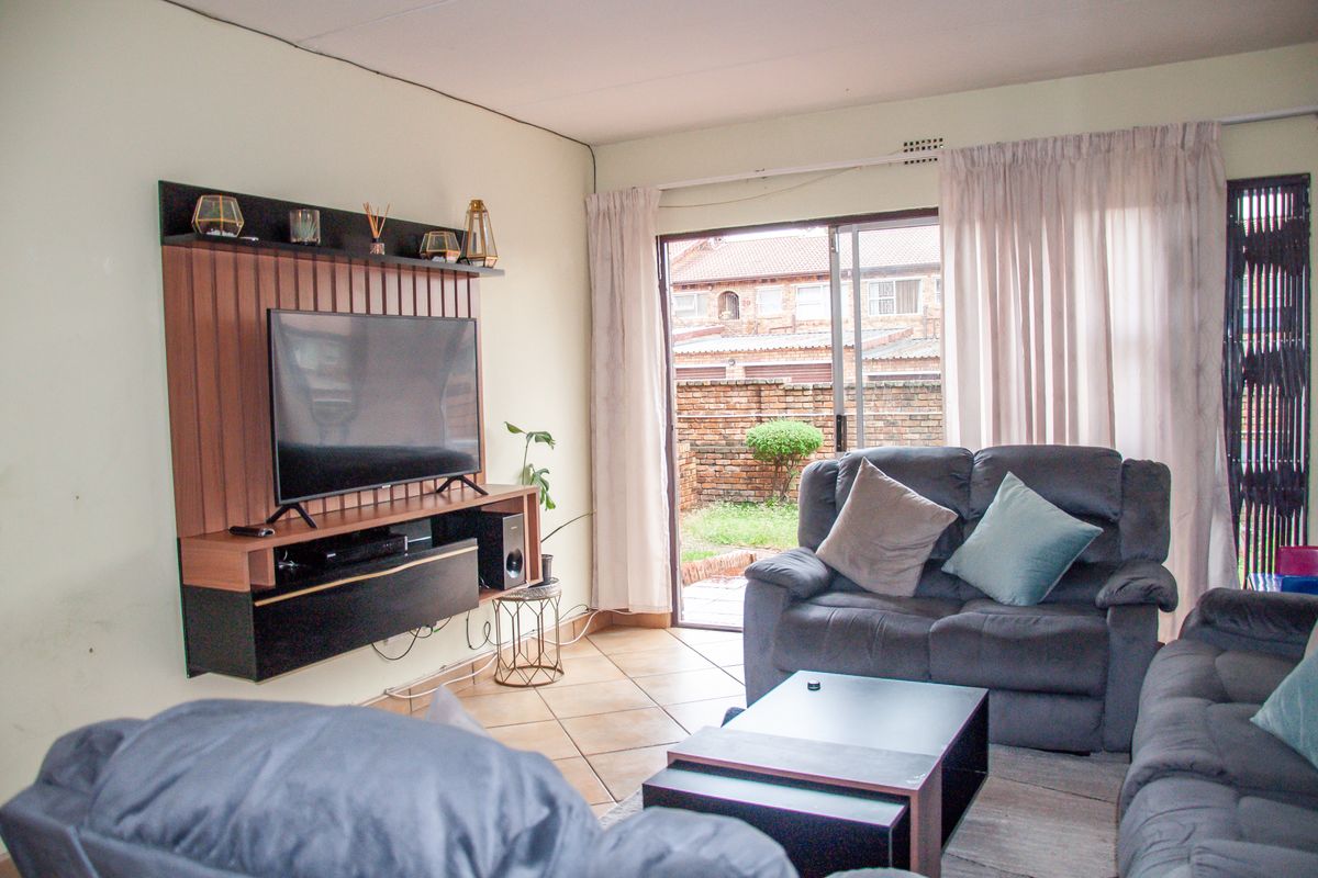 A living room featuring tiled flooring and a sliding glass door providing access to the rear exterior area.