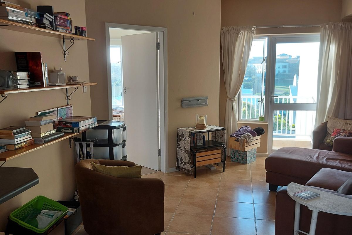 A living room featuring tiled flooring, recessed lighting, and direct access to a balcony through a glass door.