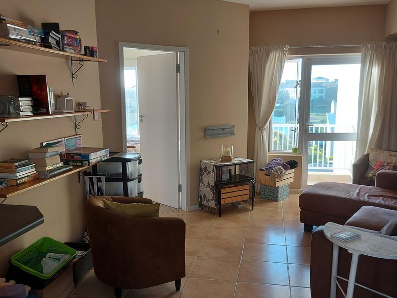 A living room featuring tiled flooring, recessed lighting, and direct access to a balcony through a glass door.