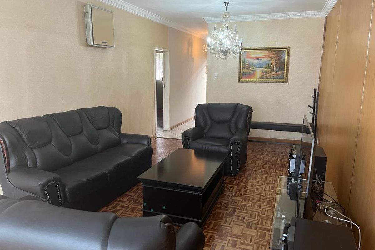 A living room featuring parquet flooring, crown molding, a crystal chandelier, and a wall-mounted air conditioning unit.