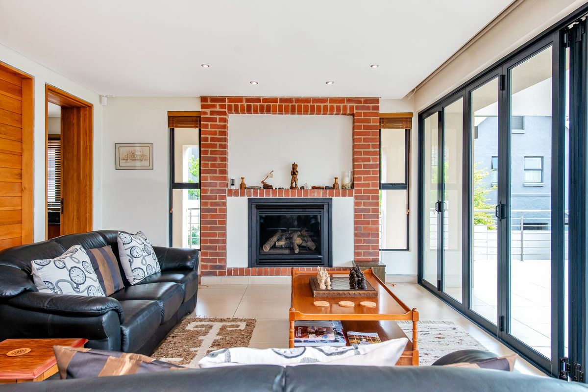 Spacious living room featuring a prominent red brick fireplace, tiled flooring, and large glass sliding doors providing seamless access to the outdoor area.