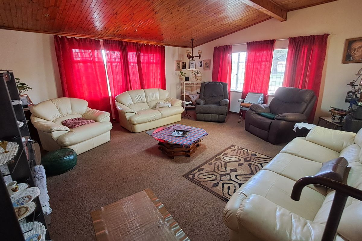 Spacious living room featuring a vaulted timber-clad ceiling with exposed beams and large windows, offering a dated but functional layout ready for modernization.