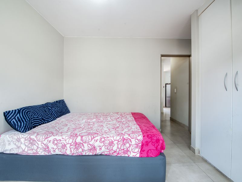 A functional bedroom featuring tiled flooring and a built-in wardrobe, providing essential storage space within the apartment.