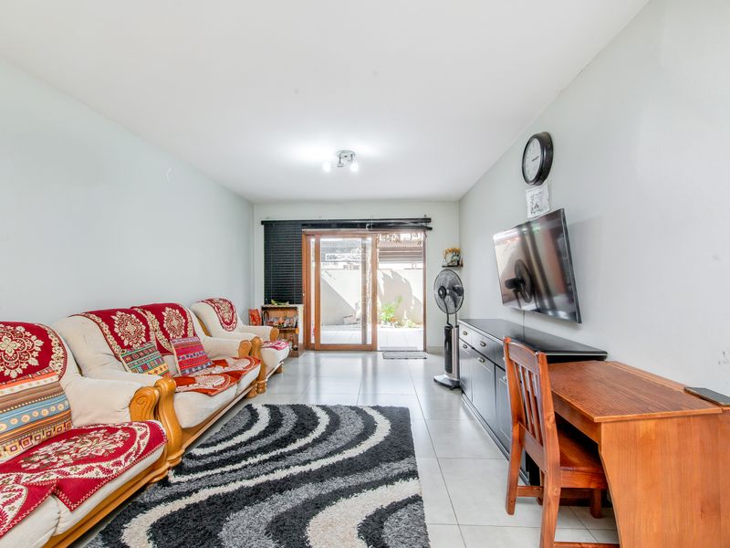 A functional living room featuring tiled flooring and a sliding glass door providing direct access to the outdoor patio area.