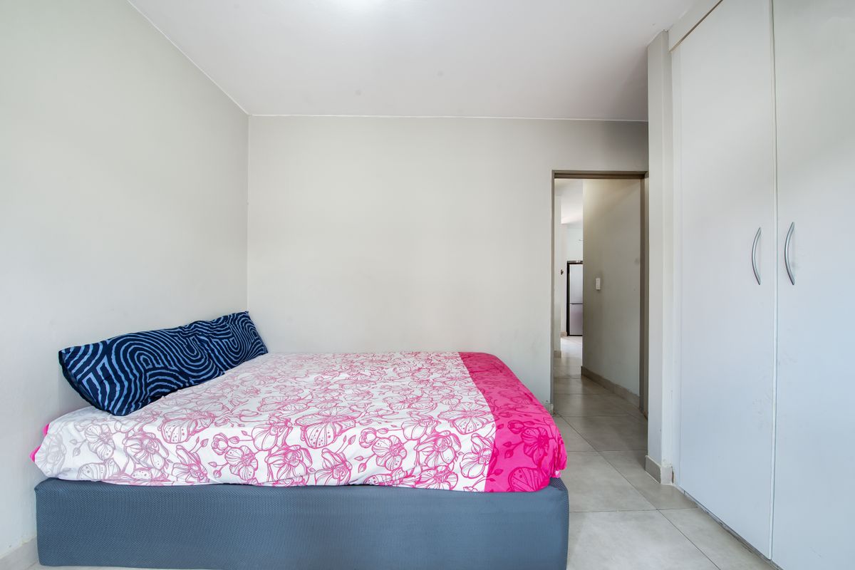 A functional bedroom featuring tiled flooring and a built-in wardrobe, providing essential storage space within the apartment.