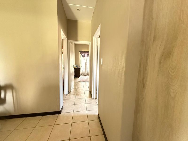 A clean, neutral-toned hallway featuring tiled flooring and recessed lighting, providing access to multiple rooms within the townhouse.