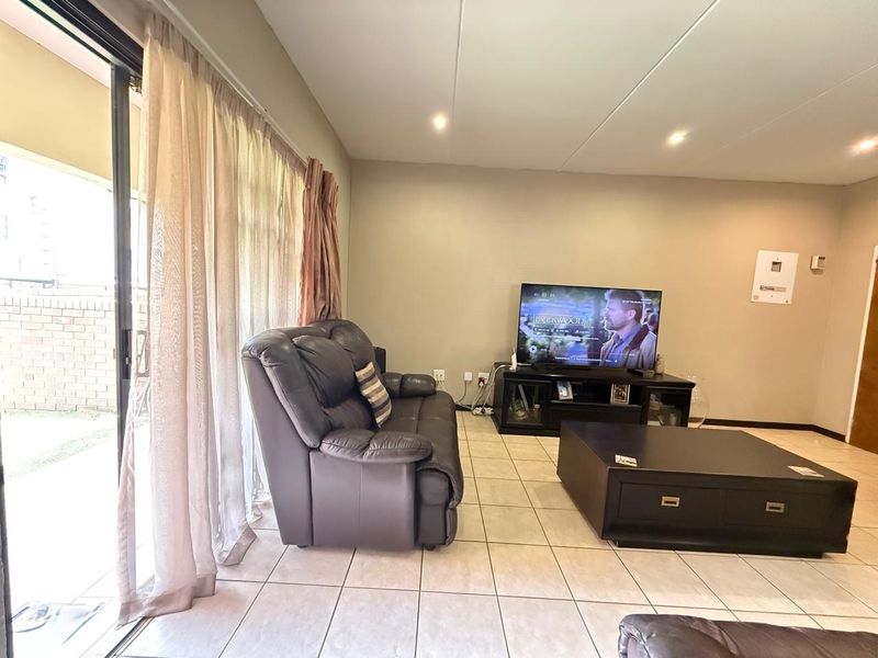 A living room featuring tiled flooring, recessed downlighting, and a large sliding glass door providing access to the outdoor area.