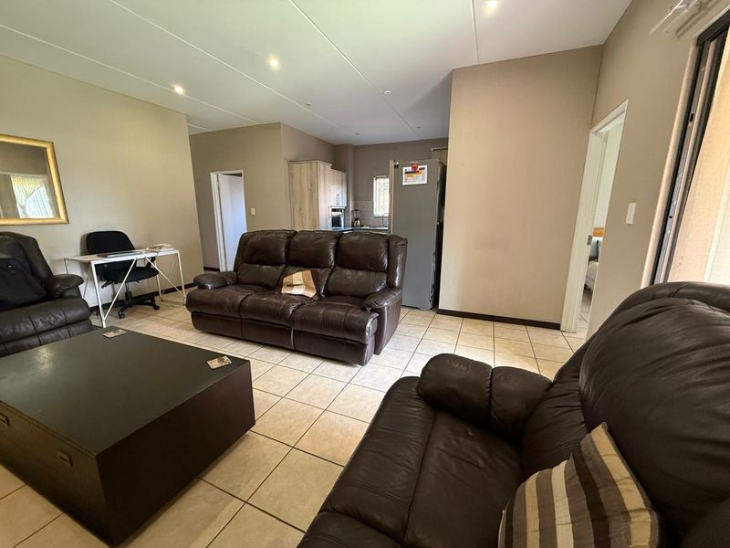 Open-plan living area featuring tiled flooring and recessed lighting, seamlessly connecting to a functional kitchen space.