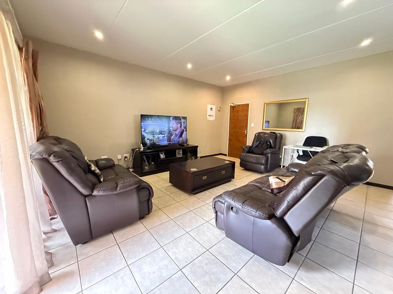 A spacious living room featuring neutral wall tones, tiled flooring, and recessed downlighting, providing a comfortable and functional area for relaxation.