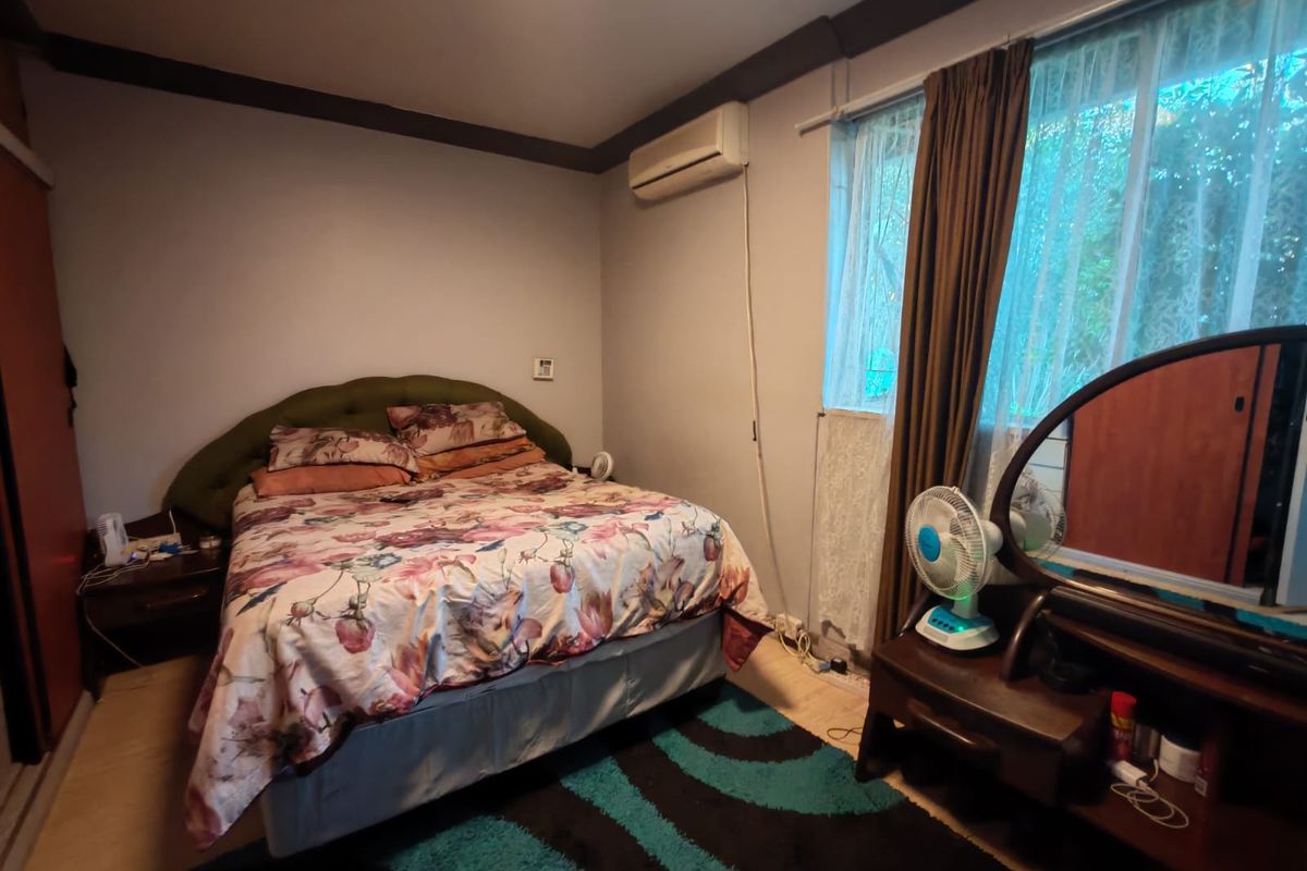 A functional bedroom featuring laminate flooring, a wall-mounted split-system air conditioner, and built-in wardrobe storage.