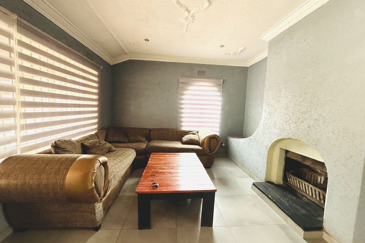 A living room featuring a built-in fireplace with a stone hearth, tiled flooring, and decorative ceiling molding.
