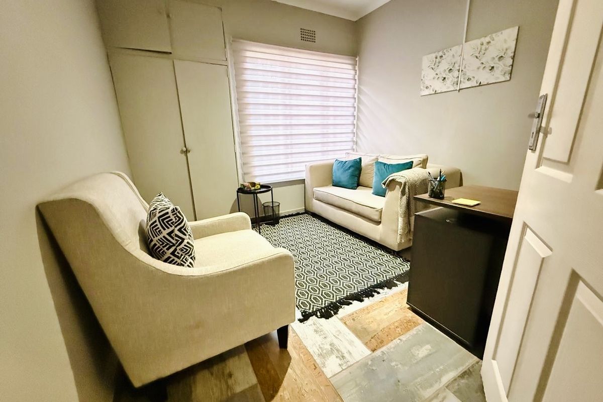 A compact bedroom or home office featuring built-in storage cupboards, neutral wall finishes, and a window with fitted blinds.