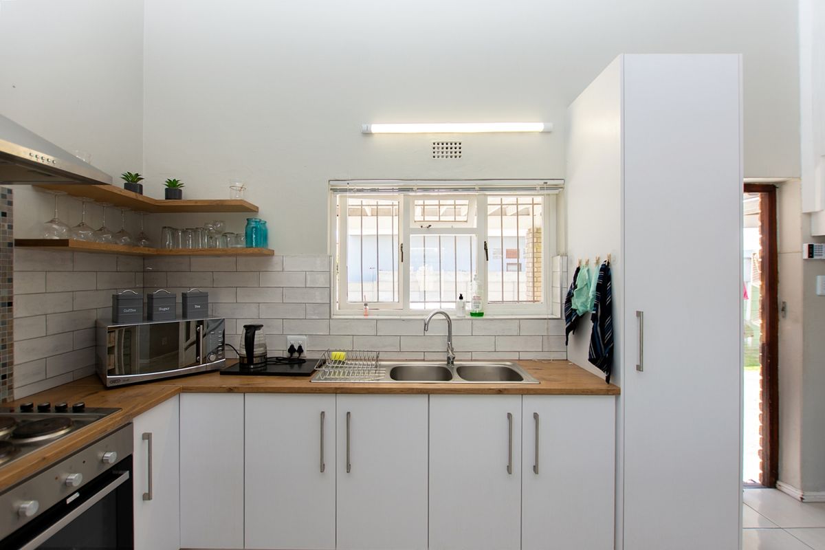 Modern kitchen featuring white cabinetry, wooden countertops, subway tile backsplash, built-in oven, gas hob, and a stainless steel double sink.