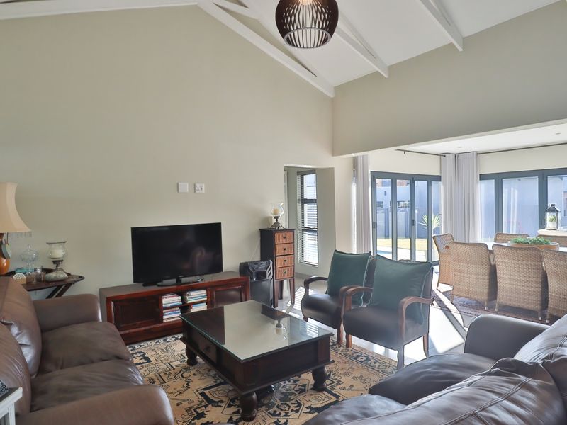 Spacious open-plan living and dining area featuring high vaulted ceilings with exposed rafters and large aluminium sliding doors leading to the outdoor space.