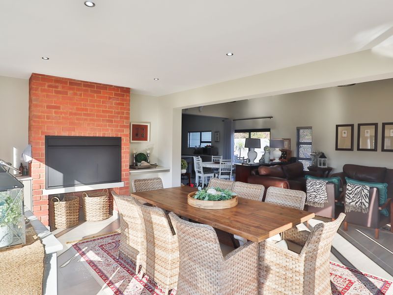 Spacious open-plan living and dining area featuring an exposed brick fireplace, recessed lighting, and neutral finishes, creating a warm and inviting atmosphere.