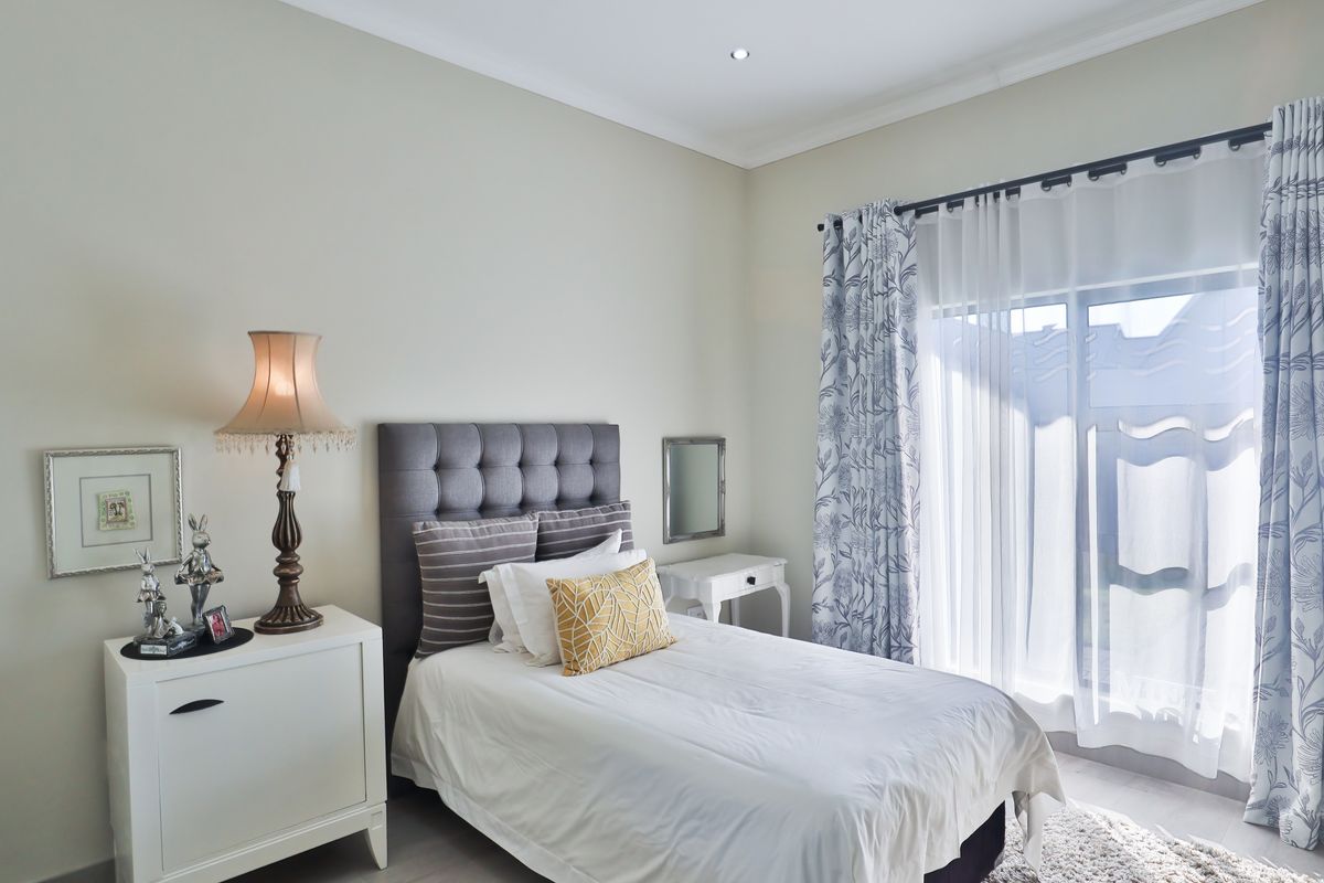 A well-maintained bedroom featuring neutral walls, recessed downlighting, and a sliding glass door providing natural light.
