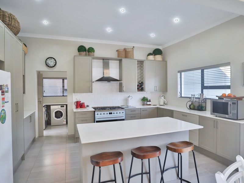 Modern kitchen featuring a central island, quartz countertops, gas stove with extractor fan, subway tile backsplash, and ample built-in cabinetry with a dedicated wine rack.
