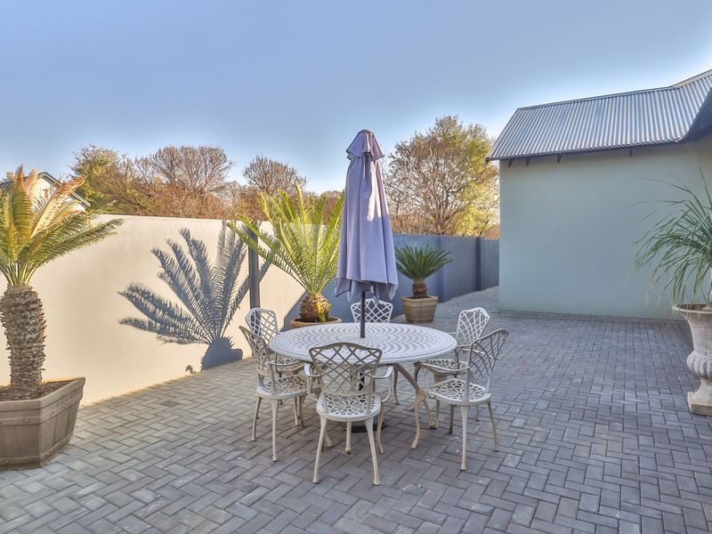 A well-maintained paved outdoor patio area featuring a boundary wall and access to the main building structure.
