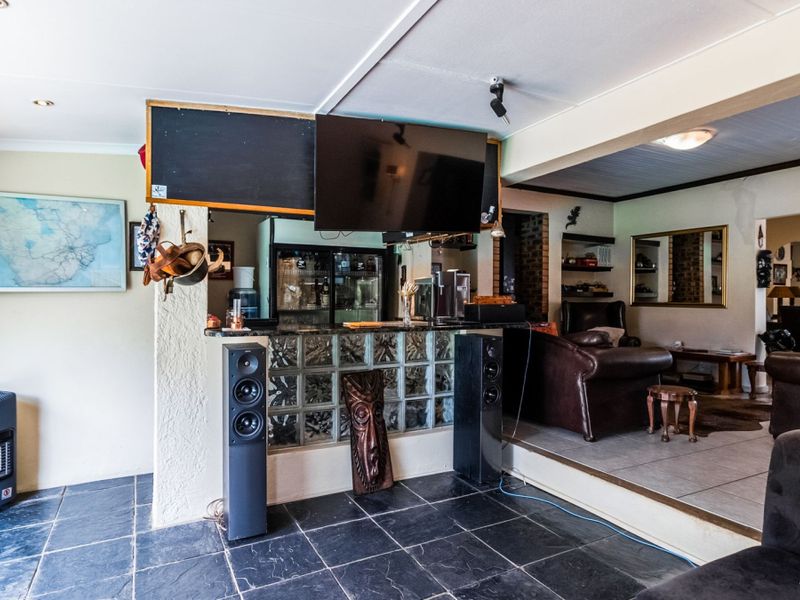 A multi-level entertainment area featuring a built-in bar with glass block detailing, tiled flooring, and recessed lighting, offering a distinct space for social gatherings.