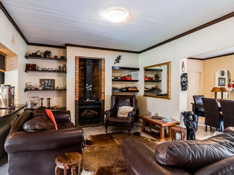 Open plan living area featuring a brick fireplace, built-in shelving, and tiled flooring, seamlessly connecting to the adjacent dining space.