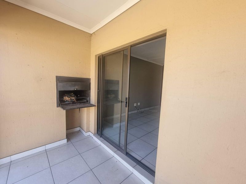 Covered patio area featuring a built-in braai and sliding glass door access to the interior living space.