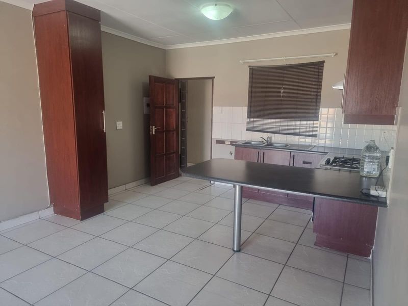 A functional kitchen featuring built-in cabinetry, a breakfast bar, gas hob, and tiled flooring, offering a clean and practical layout.