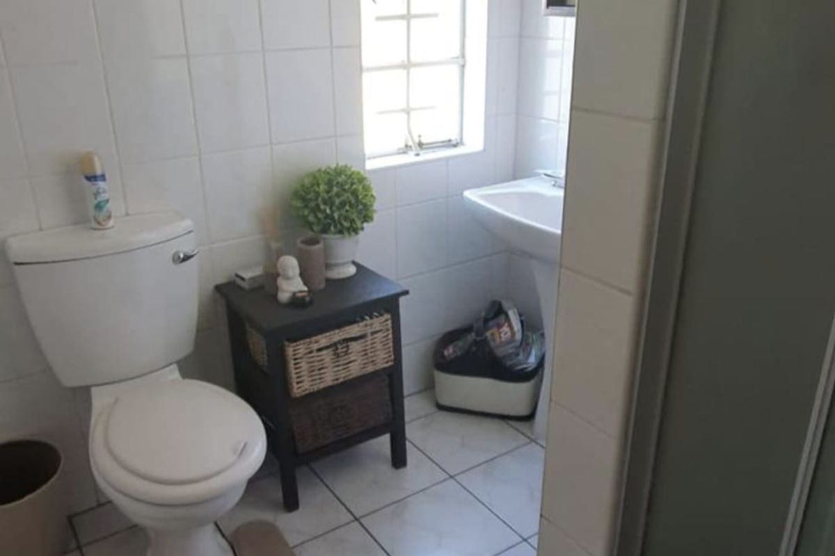 A functional bathroom featuring a pedestal basin, ceramic toilet, shower enclosure, and tiled finishes throughout.