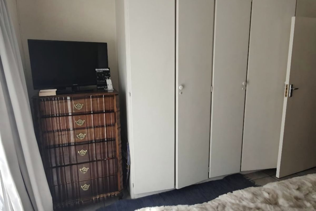 A bedroom featuring a white built-in wardrobe with multiple doors, providing ample storage space.