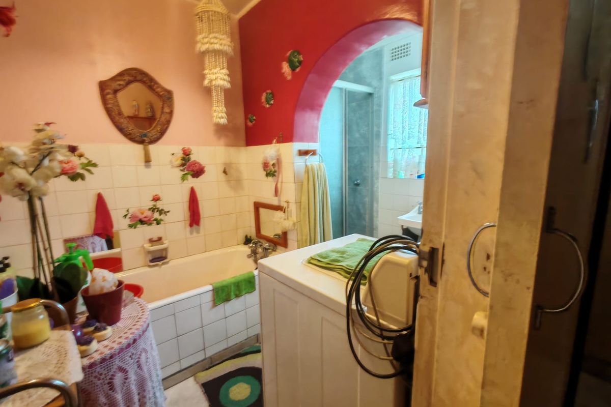 A dated bathroom featuring a built-in bathtub, tiled walls, and a separate shower enclosure accessed through a decorative archway.