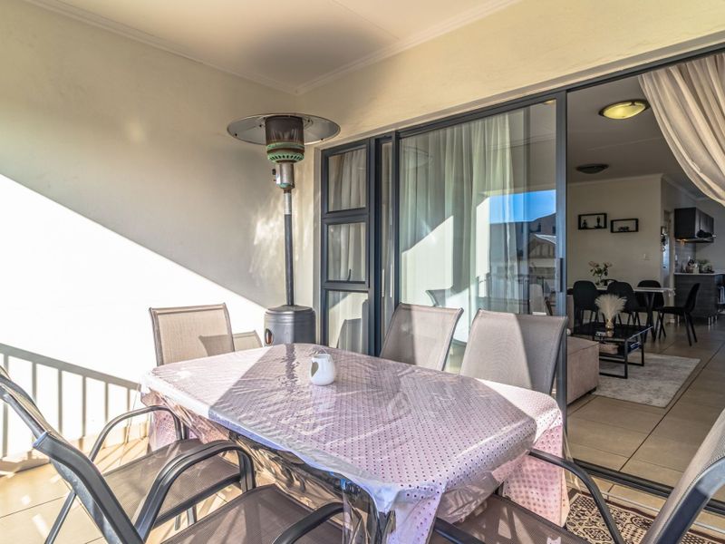 A covered balcony featuring tiled flooring and large sliding glass doors that provide seamless access to the open-plan living and dining area.
