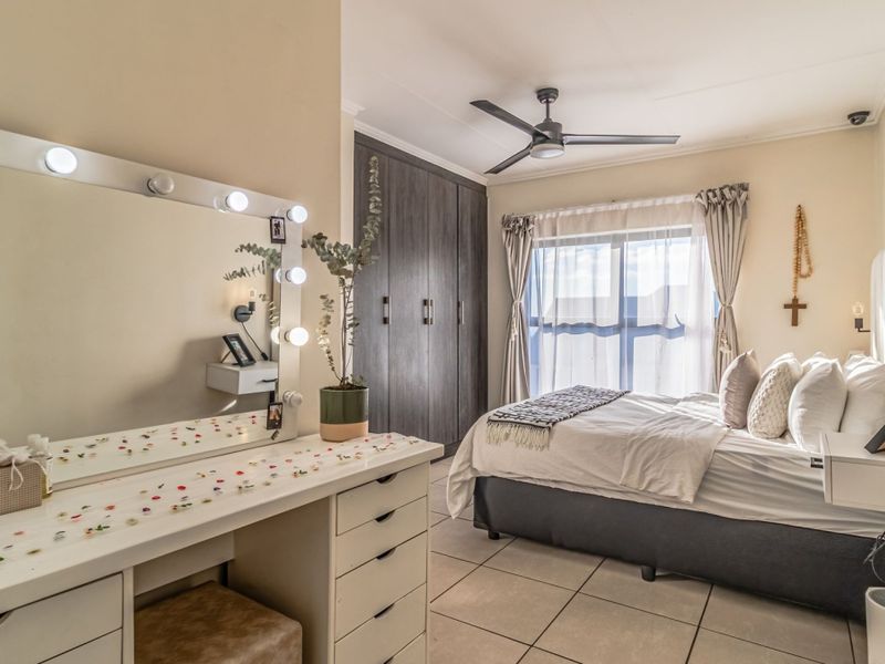 A well-maintained bedroom featuring tiled flooring, built-in cupboards, and a ceiling fan, offering a comfortable and functional living space.