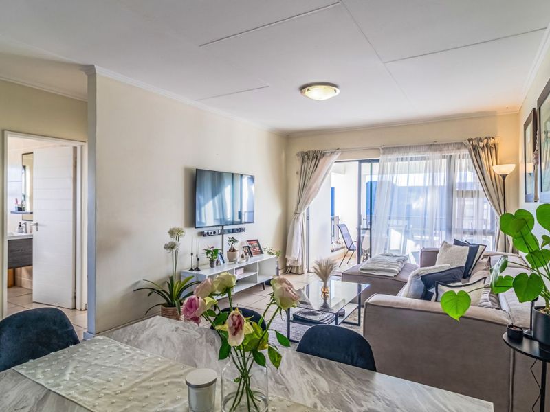 An open-plan living area featuring tiled floors, neutral walls, and a sliding glass door providing access to an outdoor balcony space.