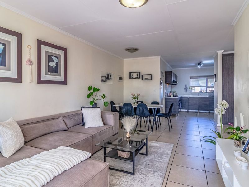 An open-plan living and dining area featuring tiled flooring, recessed lighting, and a functional kitchen with built-in cabinetry.