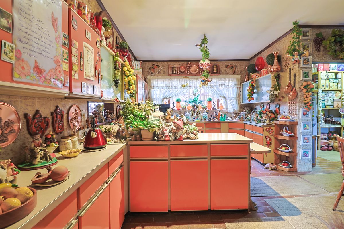 A dated kitchen featuring extensive built-in cabinetry, laminate countertops, and tiled flooring, offering significant potential for a modern renovation and layout update.