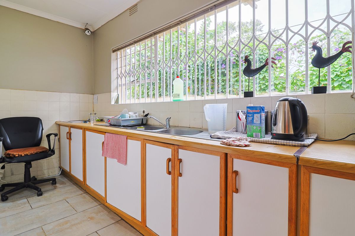 A functional kitchen area featuring a double basin sink, tiled splashback, and ample built-in cabinetry with laminate countertops.