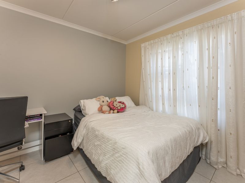 A functional bedroom featuring tiled flooring and neutral wall tones, providing a comfortable and well-lit space.