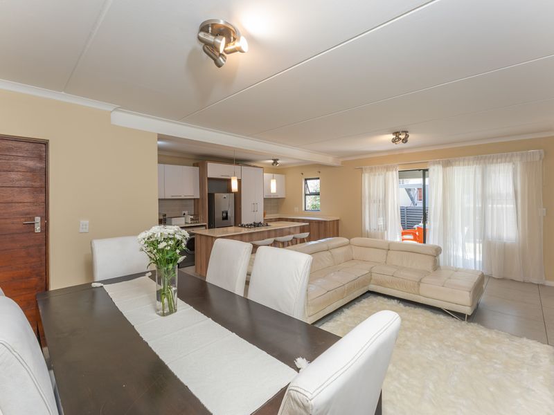 Spacious open-plan living and dining area featuring a modern kitchen with a central island, tiled floors, and direct access to an outdoor patio.