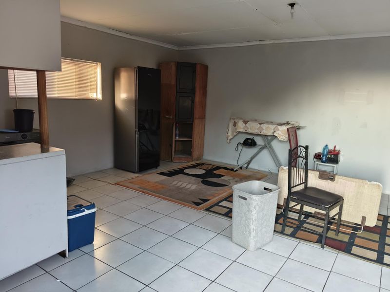 A functional laundry area featuring tiled flooring and natural light through a window, offering a blank canvas for potential renovation or utility space improvement.