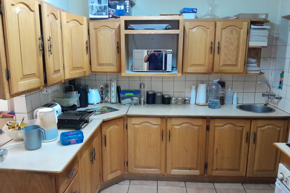 A functional kitchen featuring traditional wooden cabinetry, laminate countertops, tiled backsplash, and tiled flooring, offering a classic layout with ample storage space.
