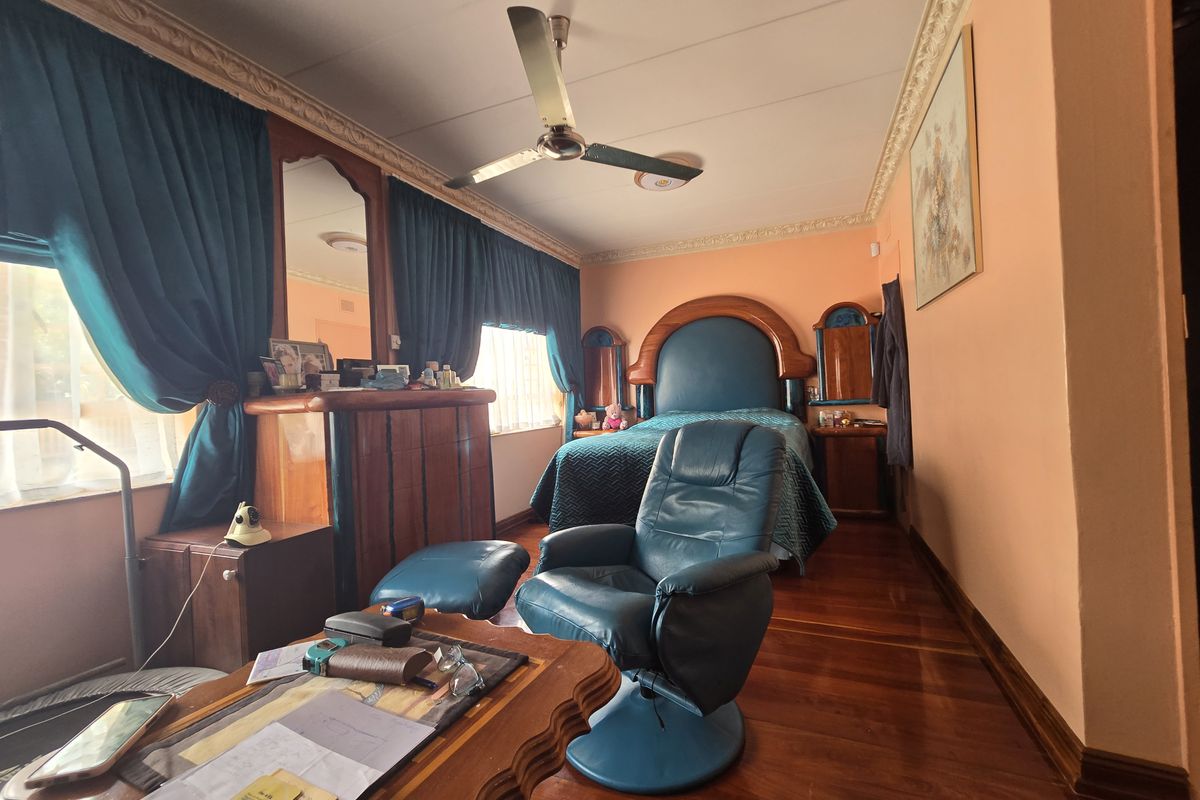 A bedroom featuring hardwood flooring, a ceiling fan, and decorative ceiling cornicing, offering a traditional layout with ample space.