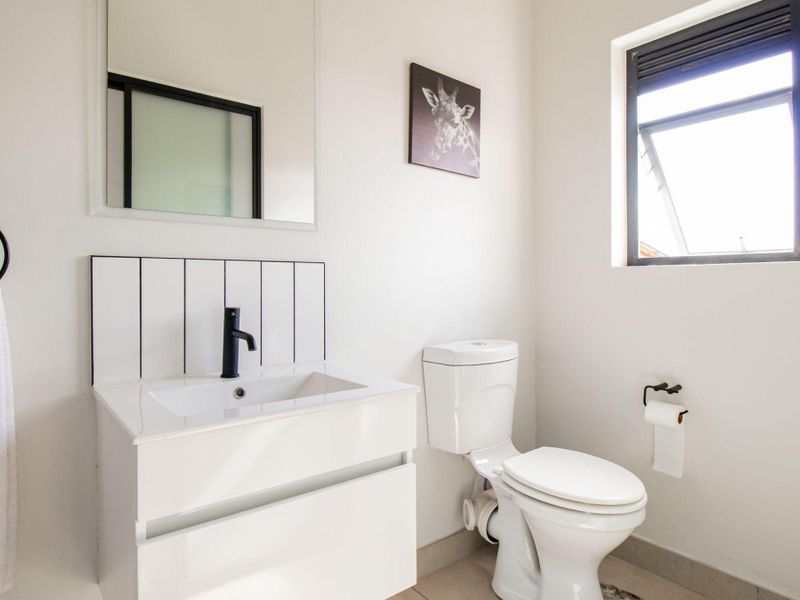 Modern bathroom featuring a sleek vanity with black fixtures, a tiled splashback, and a clean, minimalist design.