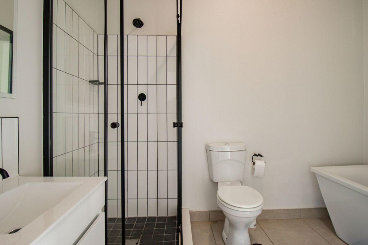 Modern bathroom featuring a freestanding bathtub, a separate shower enclosure with black framing, and a vanity basin with contemporary black fixtures.