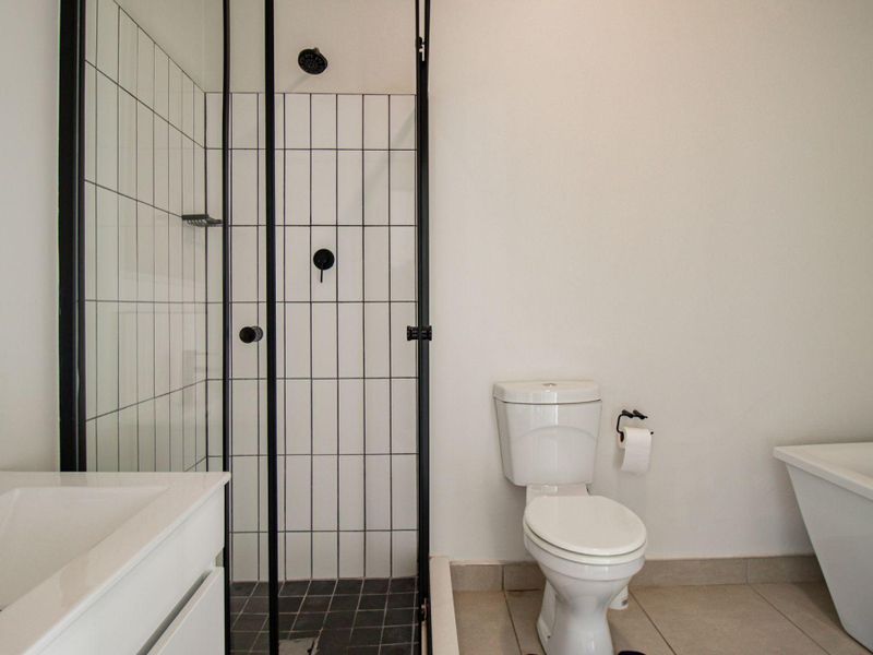 Modern bathroom featuring a freestanding bathtub, a separate shower enclosure with black framing, and a vanity basin with contemporary black fixtures.
