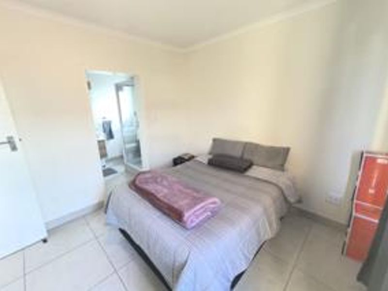 A functional bedroom featuring tiled flooring and direct access to an en-suite bathroom, offering a clean and simple living space.