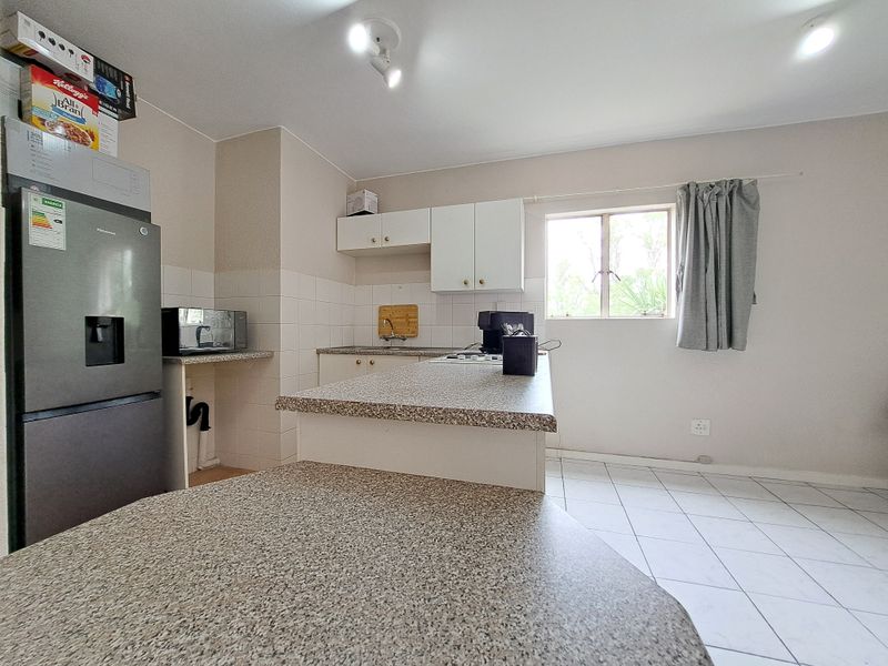 A functional kitchen featuring laminate countertops, tiled backsplash, and built-in cabinetry with ceramic floor tiles.