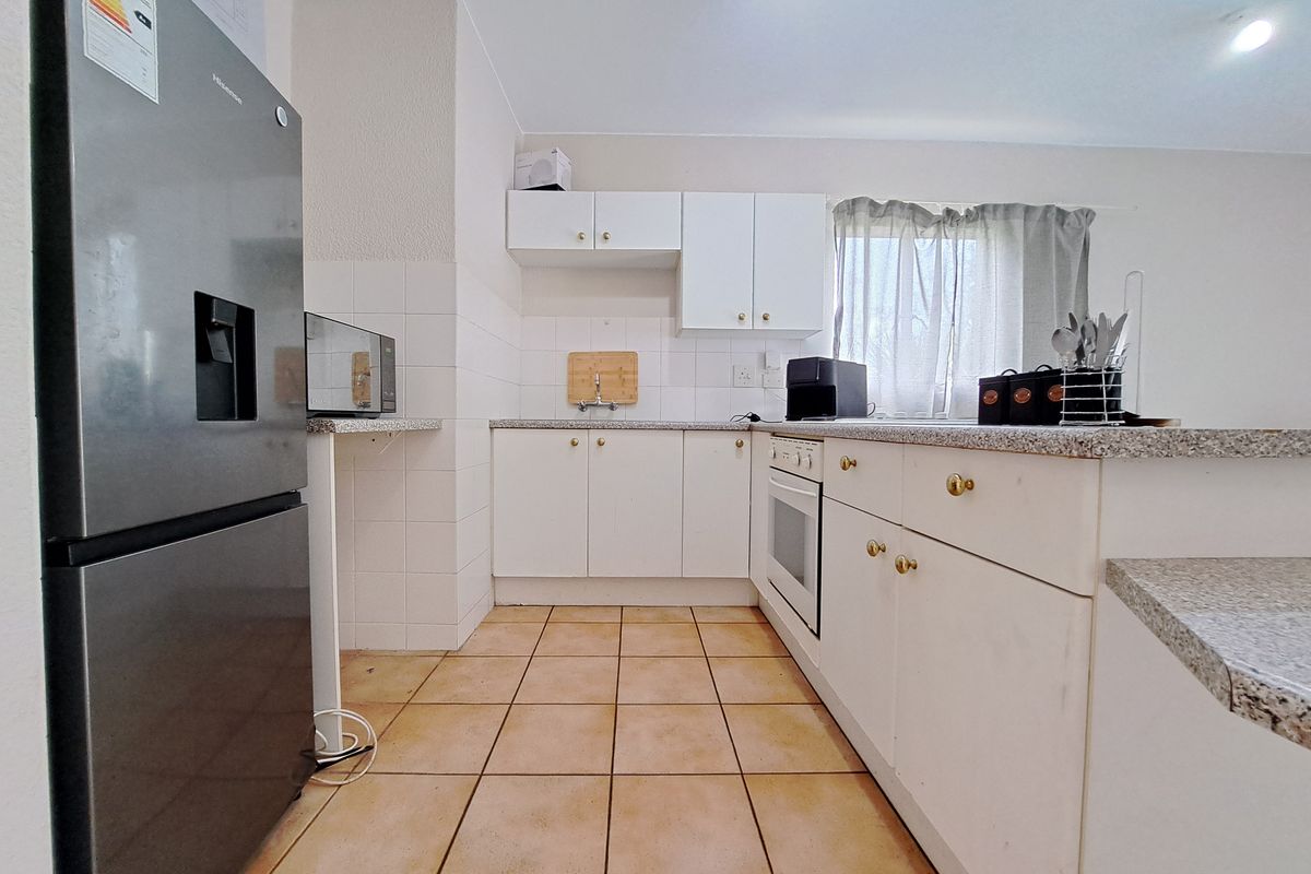A functional kitchen featuring white cabinetry, granite countertops, a built-in oven, and tiled flooring, offering a clean and practical workspace.