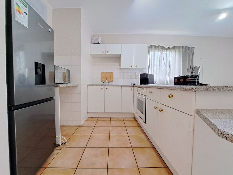 A functional kitchen featuring white cabinetry, granite countertops, a built-in oven, and tiled flooring, offering a clean and practical workspace.