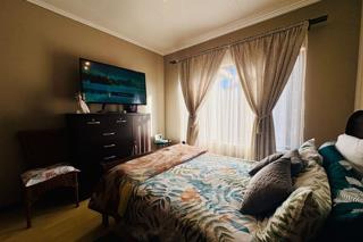A cozy bedroom featuring laminate flooring and a window dressed with curtains, providing a comfortable and functional sleeping space.